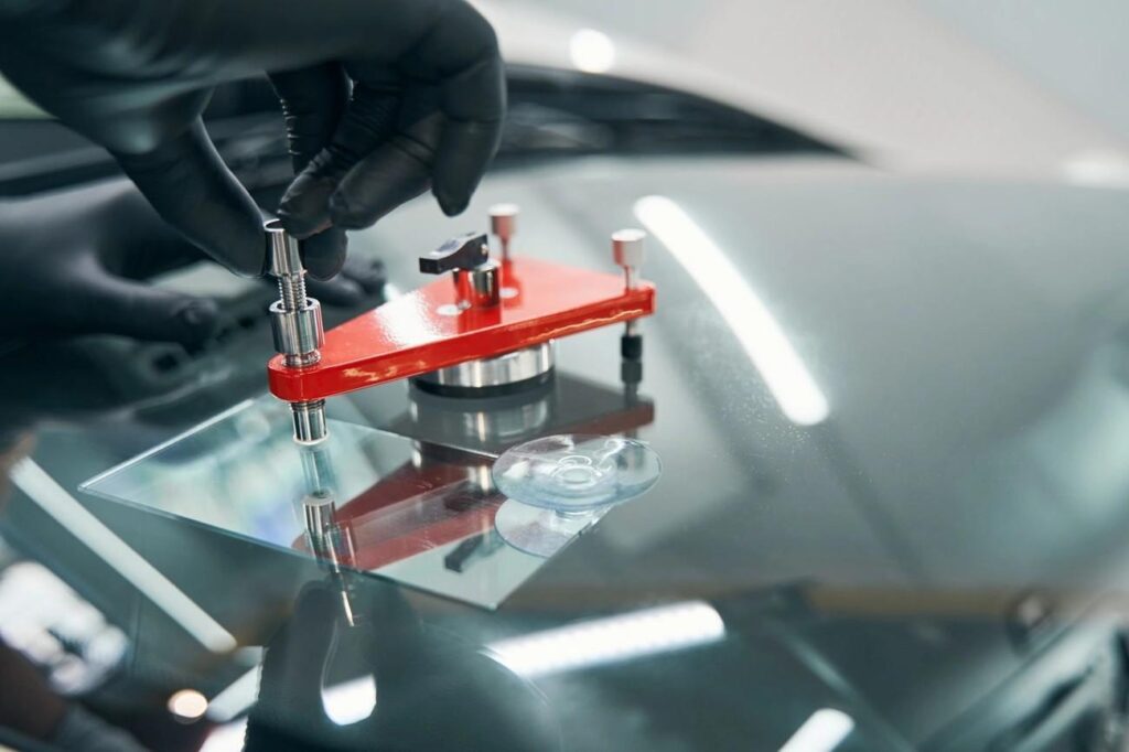 Close-up of a technician from Expert Auto Glass in Surrey using a professional resin injection tool to repair a rock chip on a vehicle's windshield.